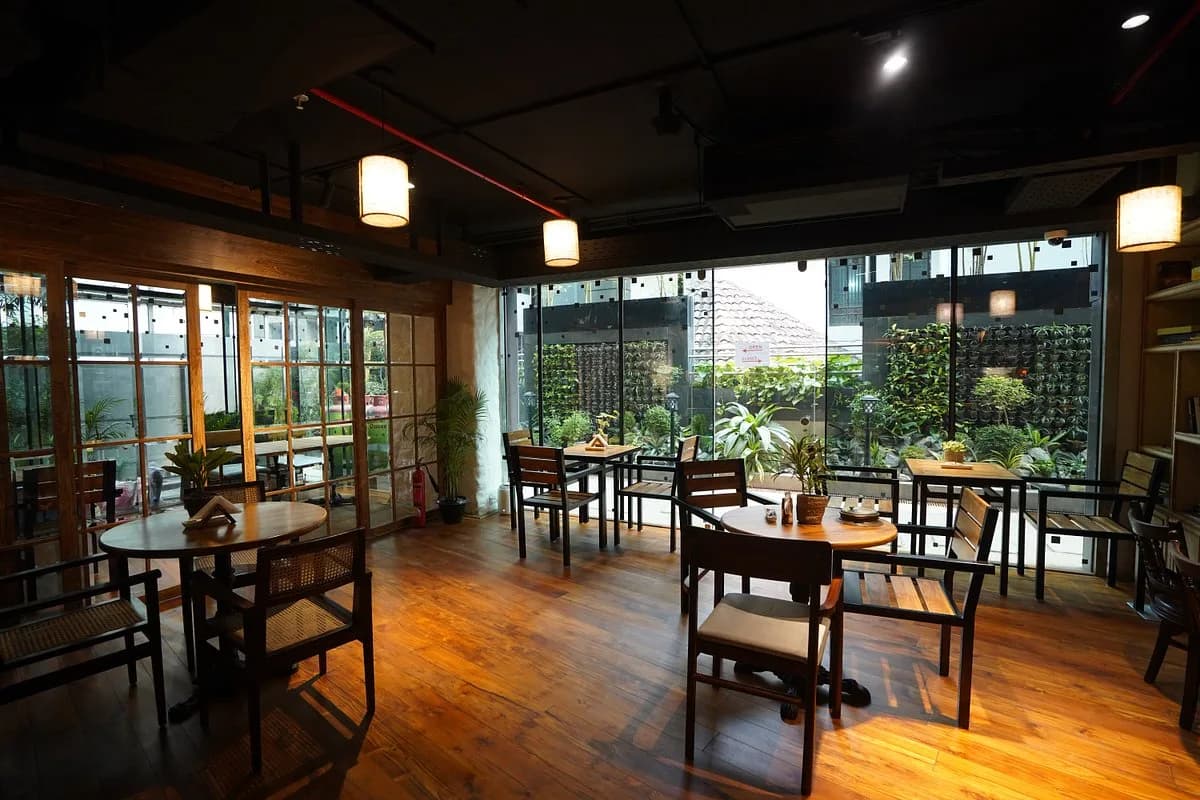 Warm cafe interior with wooden tables and seating overlooking a green garden