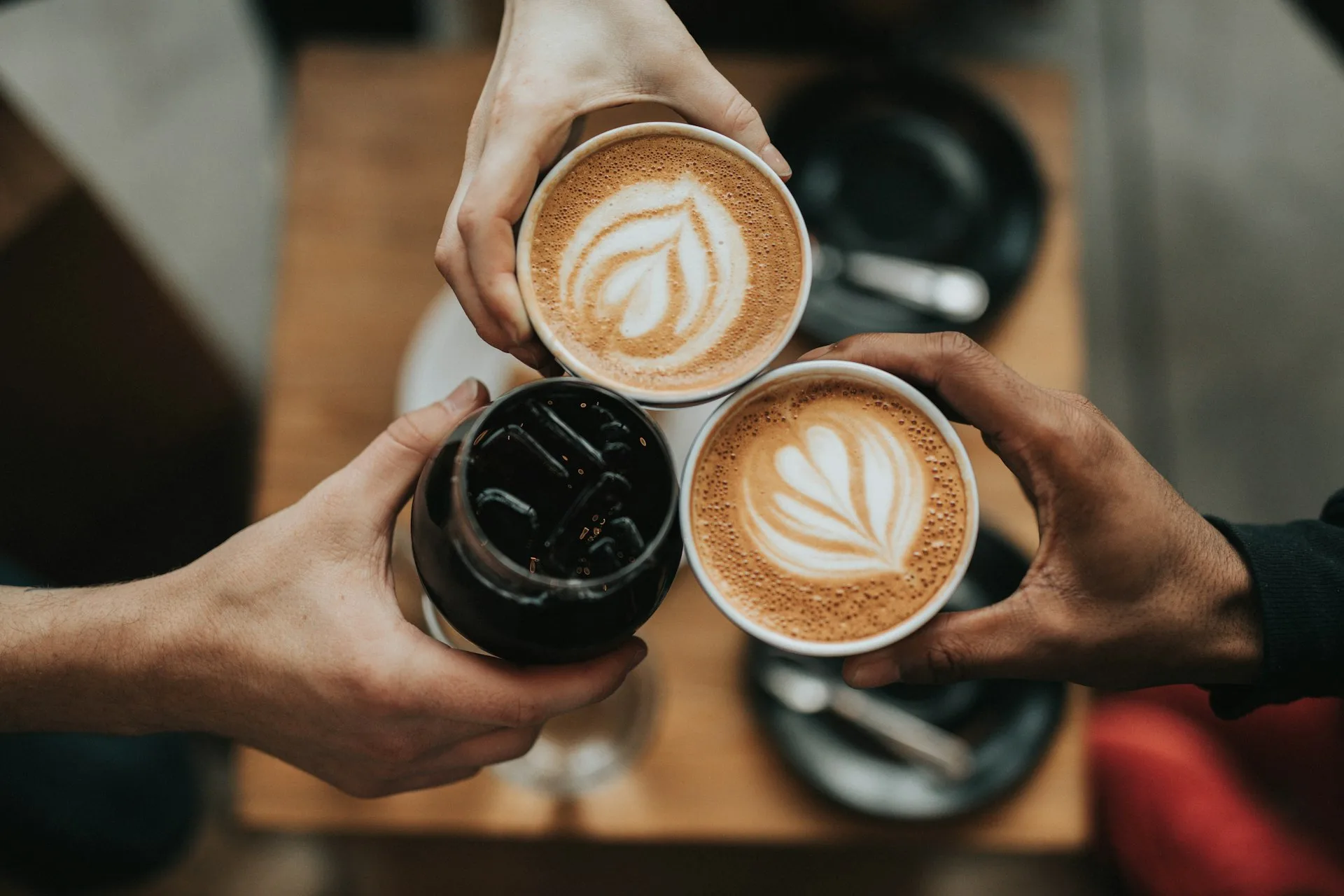 Three people holding coffee cups together at a cafe